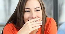 Laughing young woman covering her mouth with her hand