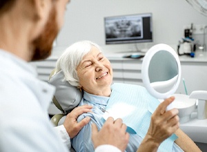 Senior woman admiring her new implant denture in mirror