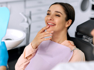 Happy dental patient looking at her smile in mirror