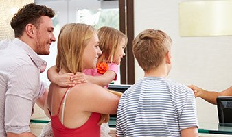 Family of four talking to dental team member at front desk