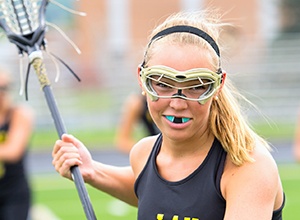 Girl playing lacrosse wearing mouthguard