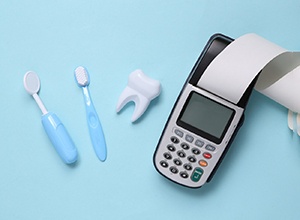 Calculator next to fake tooth and dental tools