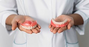 Dental professional holding upper and lower dentures