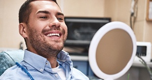 Happy patient using mirror to admire his dental implant restorations