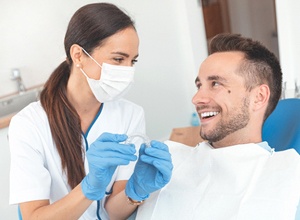 Dentist explaining the cost of Invisalign in Meriden to happy patient