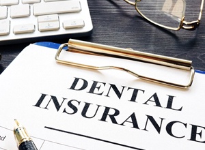 Dental insurance form and pen on blue clipboard