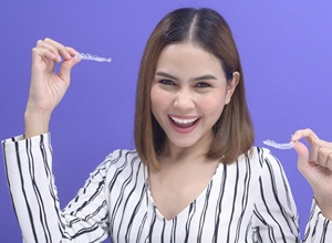 Woman holding her Invisalign aligners, happy she could afford treatment