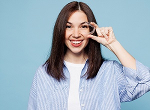 Happy woman holding an Invisalign aligner