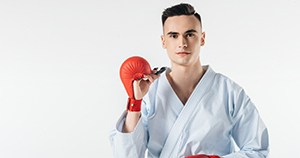 Young athlete in martial arts robe holding mouthguard