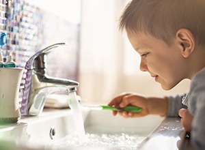 Little boy running toothbrush under water