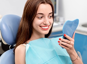 Woman looking at newly whitened teeth in mirror