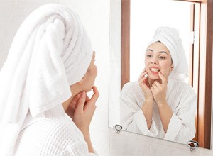 Woman inspecting her teeth in bathroom mirror