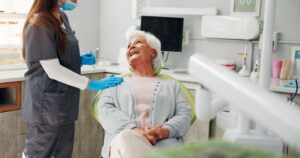 Smiling senior patient talking with dental team member