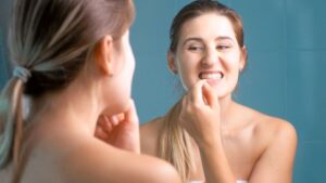 Woman inspecting her teeth in bathroom mirror 