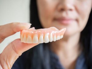 Close-up of person holding denture for upper arch