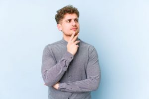 Curious man in gray shirt against blue background