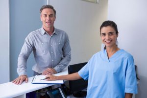 Patient and dental team member standing at dental office front desk