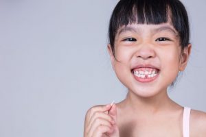 Smiling child holding her extracted tooth