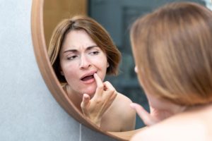 Woman in front of mirror, inspecting her teeth