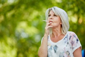 Woman sitting outside, smoking cigarette