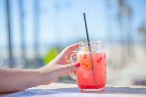 Woman’s hand reaching for drink with a straw in it