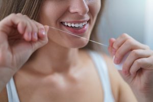 woman flossing to maintain dental hygiene during quarantine